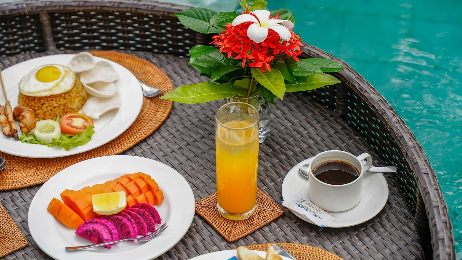Illustrative photo of a breakfast tray with fruit, fried rice, juice and coffee by a pool