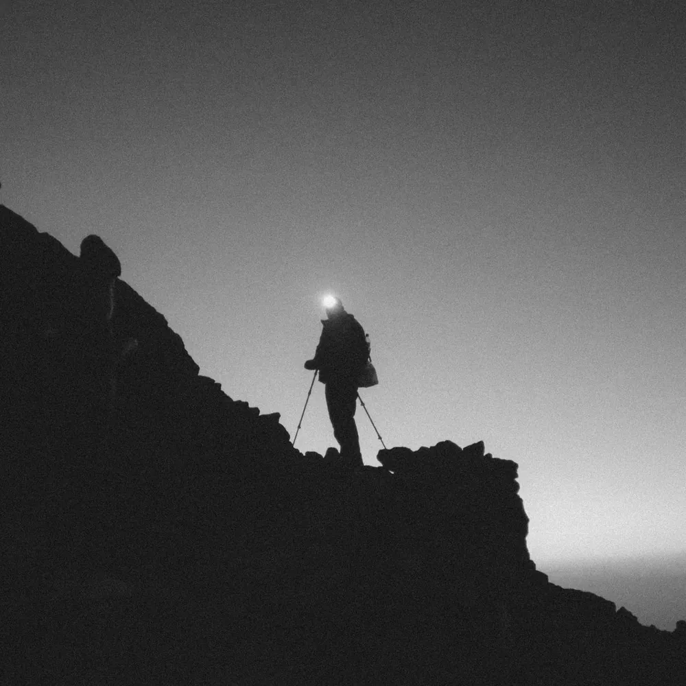 Illustrative photo of a hiker with a head torch on a dark mountain ridge