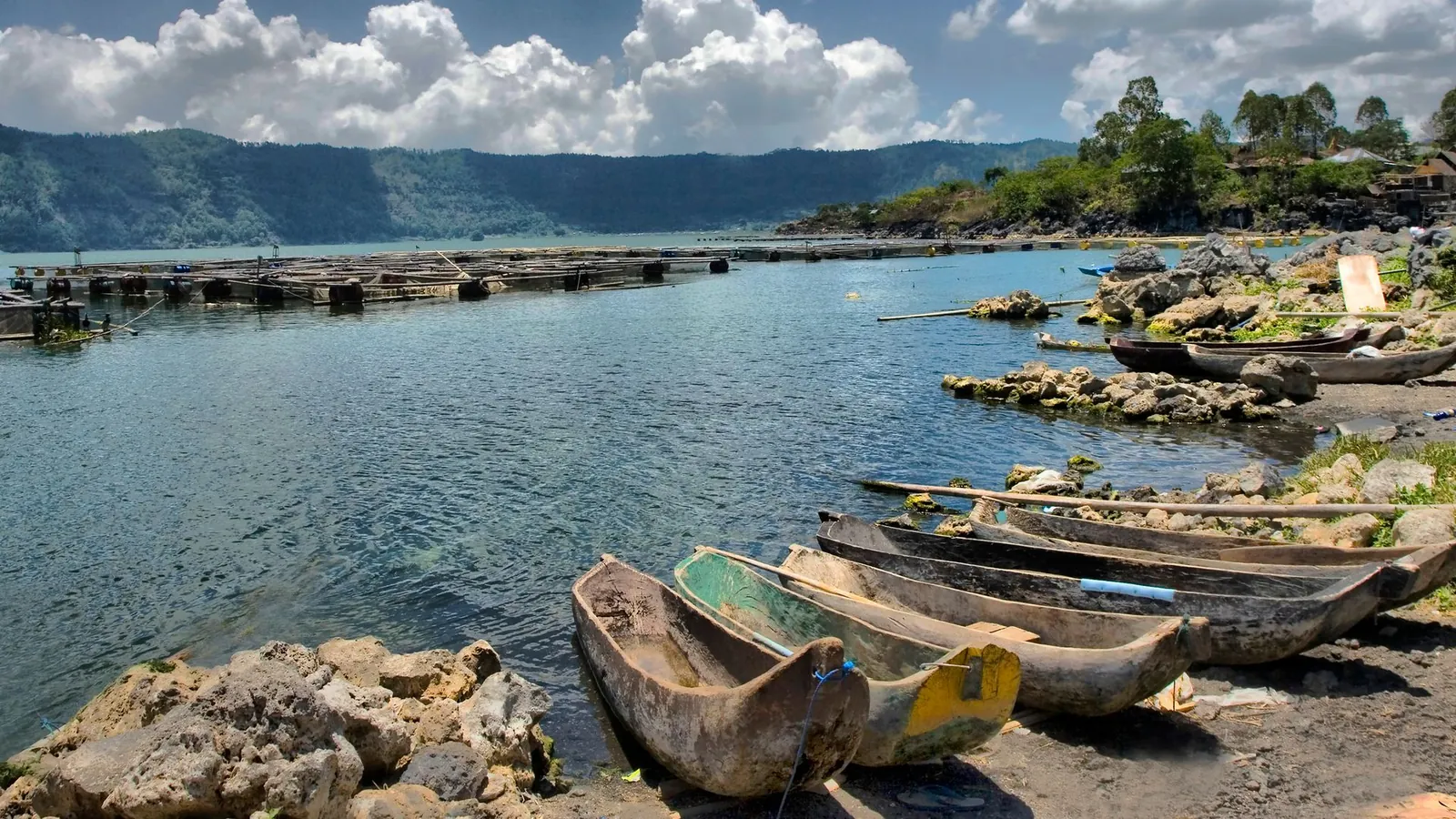 Illustrative photo of wooden canoes on the shore of Lake Batur with the mountains behind