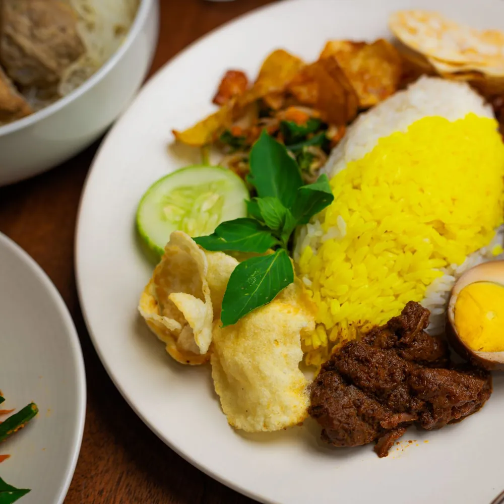 Illustrative photo of an Indonesian rice plate with yellow rice, egg and sambal